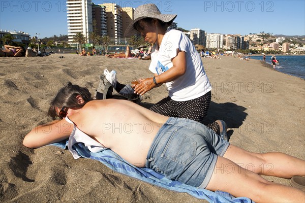 Woman having a massage on Playa de Malagueta sandy beach, Malaga, Spain, Europe