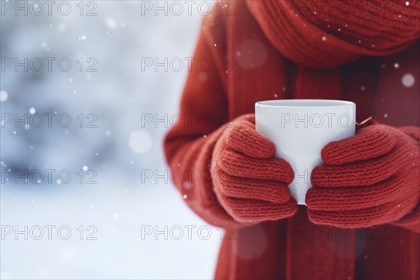 Close up of person with red knitted gloves holding mug with tea or coffee in snow. KI generiert, generiert, AI generated