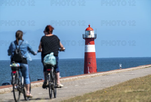 North Sea dyke near Westkapelle, Westkapelle Laag lighthouse, cyclists on the Zeeuwse Wind Route cycle path, province of Zeeland, Walcheren peninsula, Netherlands