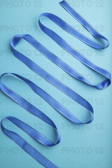 Blue ribbon on a blue pastel background. Celebration concept. Top view, close up, flat lay