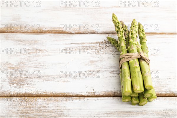 Bunch of fresh green asparagus on white wooden background. Side view, copy space. harvest, healthy, vegan food, concept, minimalism