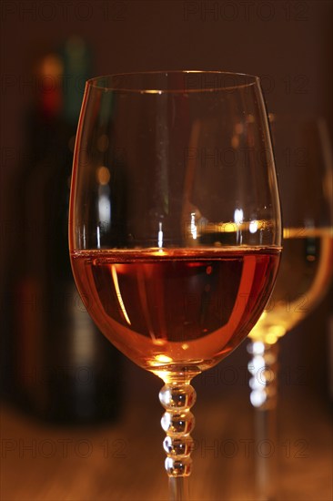 Close-up of two glasses of wine with wine bottles in the background