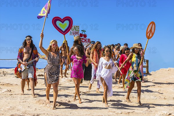 Colourfully dressed youths with musical instruments and banners form a love parade and promote the nightclub Pacha, Cala Comte, Ibiza, Balearic Islands, Mediterranean Sea, Spain, Europe