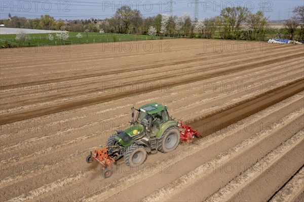 A farmer builds asparagus ridges on a field with the help of an asparagus tiller, in which the asparagus then grows, Dormagen, North Rhine-Westphalia, Germany, Europe