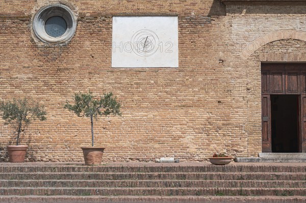 Brick wall with sundial, olive trees in pots and steps in a Mediterranean setting, Tuscany, Italy, Europe