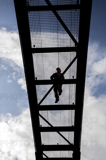 Lattice walkway, people walk over a walkway at a height of a good 15 metres, made of steel lattice, seen from below, viewing platform