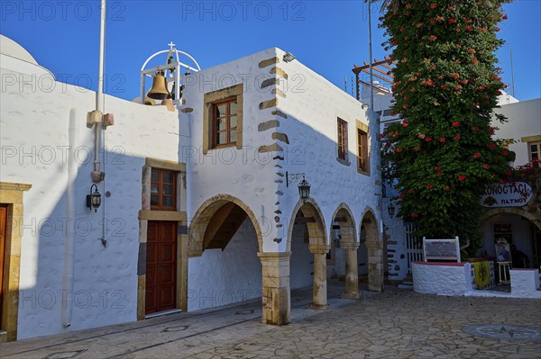 Agios Ioannis Prodromos Church, A whitewashed, historic church building with bell on a Greek island, surrounded by cobblestones and trees, Skala, Patmos, Dodecanese, Greek Islands, Greece, Europe