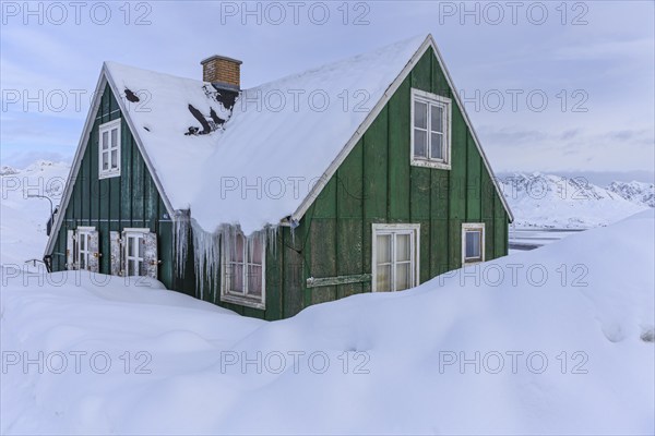 Typical Greenlandic house in deep snow in front of mountains, winter, Tasiilaq, East Greenland, Greenland, North America