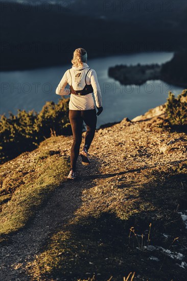 Trail running in autumn on the Jochberg on Lake Walchensee against the wonderful backdrop of the Alps, Bavaria, Germany, Europe