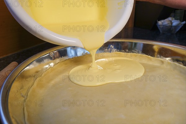 Swabian cuisine, preparation of salted cream cake with spring onions, hearty cake, salty shortcrust, baked, raw dough in springform pan, add cream mixture, baking tin, cake tray, worktop, mixing bowl, out of the oven, baked goods vegetarian, typical Swabian reinterpreted, baking, traditional cuisine, food photography, studio, Germany, Europe