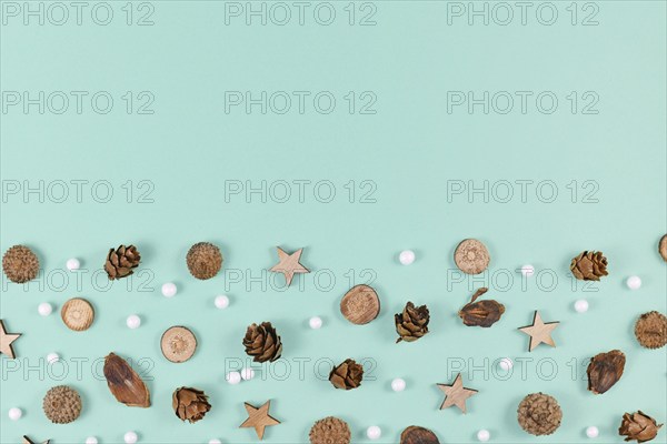 Seasonal decoration like wood slices and cones and Christmas star and snowball ornaments on mint green background with empty copy space