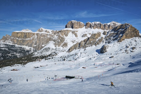 View of a ski resort piste with people skiing in Dolomites in Italy. Ski area Belvedere. Canazei, Italy, Europe