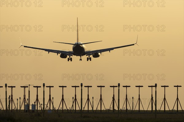 Boeing 737 jet passenger aircraft on approach to land at sunset over landing lights, London Stansted airport, Essex, England, United Kingdom, Europe