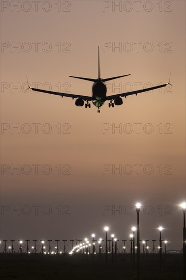 Boeing 737 jet passenger aircraft on approach to land at sunset over landing lights, London Stansted airport, Essex, England, United Kingdom, Europe