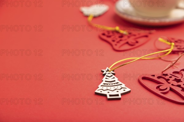 Christmas or New Year composition. Decorations, fir and spruce branches, cup of coffee, on a red paper background. Side view, selective focus, copy space