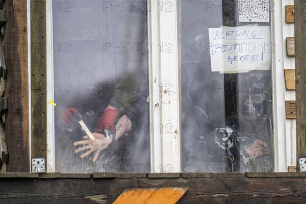 2nd day of the eviction of the hamlet Lützerath, by the police, of tree houses and huts, activist has glued herself to the glass pane of a window, from the inside, police removes the glue, at the opencast lignite mine Garzweiler 2, Erkelenz, North Rhine-Westphalia, Germany, Europe