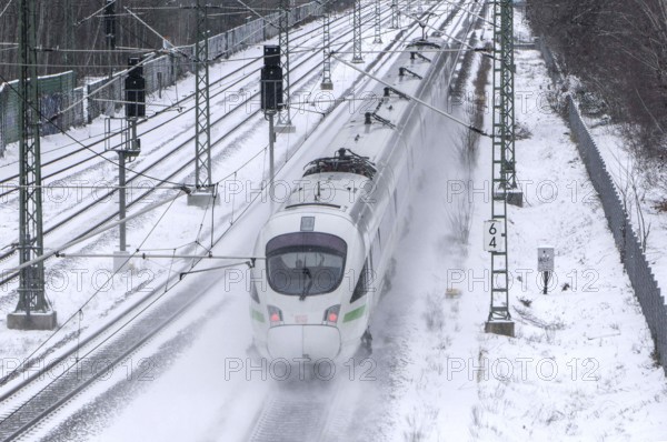 A Deutsche Bahn ICE train drives over snow-covered railway tracks and stirs up snow, Berlin, 09/02/2021