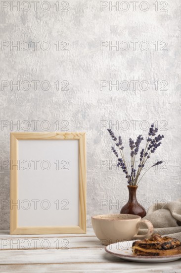 White wooden frame mockup with lavender in ceramic vase, linen textile, cup of coffee and bun on gray concrete background. Blank, vertical orientation, still life