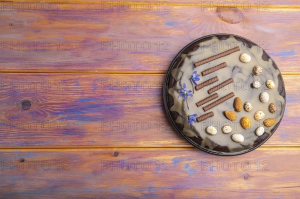 Homemade chocolate brownie cake with caramel cream and almonds on a colored wooden background. top view. flat lay, copy space