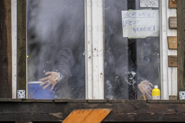 2nd day of the clearing of the hamlet Lützerath, by the police, of tree houses and huts, activist has taped herself to the glass pane of a window, from the inside, at the opencast lignite mine Garzweiler 2, Erkelenz, North Rhine-Westphalia, Germany, Europe