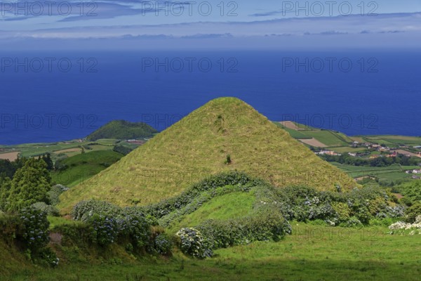 An isolated, green volcanic hill stands out, surrounded by agriculture and dense vegetation, Caldeira das Sete Cidades, Sete Cidades, Sao Miguel Island, Azores, Portugal, Europe