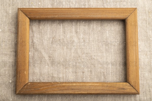 Wooden frame on smooth white linen tissue. Top view, flat lay, natural textile background and texture