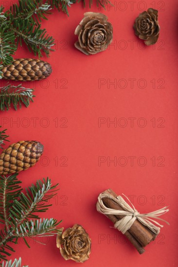 Christmas or New Year composition. Decorations, box, cinnamon, cones, fir and spruce branches, cup of coffee, on a red paper background. Top view, copy space, flat lay