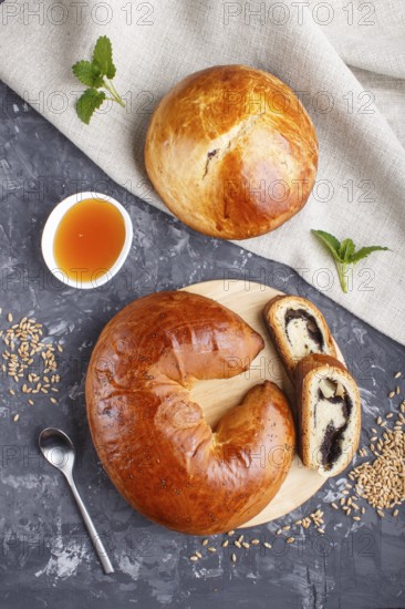 Homemade yeast buns and rolls with poppy seeds and honey on a black concrete background. top view, flat lay