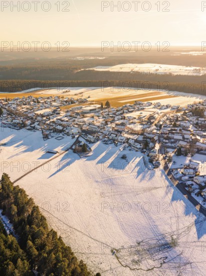 Aerial view of a snow-covered village next to a dense forest in the soft light of late afternoon, Simmersfeld, Calw district, Black Forest, Germany, Europe