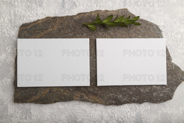 White paper business card, mockup with natural stone and boxwood branch on gray concrete background. Blank, flat lay, top view, still life, canvas, copy space