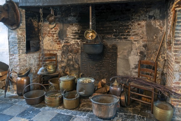 Old pots, cauldrons and kettles in hearth, open fireplace at kitchen inside Kasteel van Laarne, 14th century medieval castle, East Flanders, Belgium, Europe