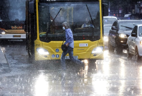 People run across Potsdamer Strasse in heavy rain. After weeks of heat, the first heavy rain brought cooling, Berlin, 15.08.2022