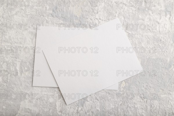 White paper business card, mockup on gray concrete background. Blank, flat lay, top view, still life, copy space