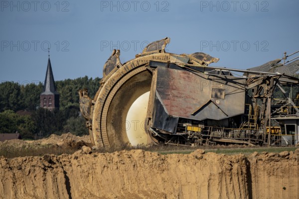 Opencast lignite mine Garzweiler II, bucket wheel excavator during excavation, at the edge of the opencast mine near the village of Keyenberg, village church, belongs to Erkelenz in the district of Heinsberg, North Rhine-Westphalia, Germany, Europe