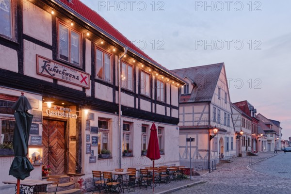 A festively illuminated restaurant in the evening and half-timbered houses in the cobbled Kirchstraße in the old town of Tangermünde, Hanseatic town in the Altmark. Saxony-Anhalt, Germany, Europe