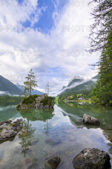 Hintersee with rocks and trees in the foreground, surrounded by mountains, cloudy sky, Ramsau, Berchtesgaden National Park, Berchtesgadener Land, Upper Bavaria, Bavaria, Germany, Europe