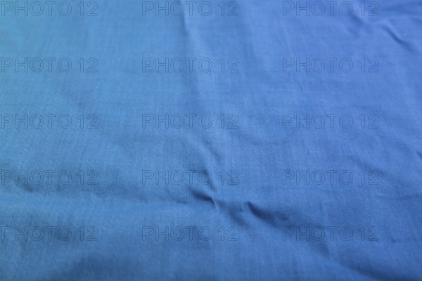 Fragment of smooth cotton blue tissue. Side view, natural textile background and texture