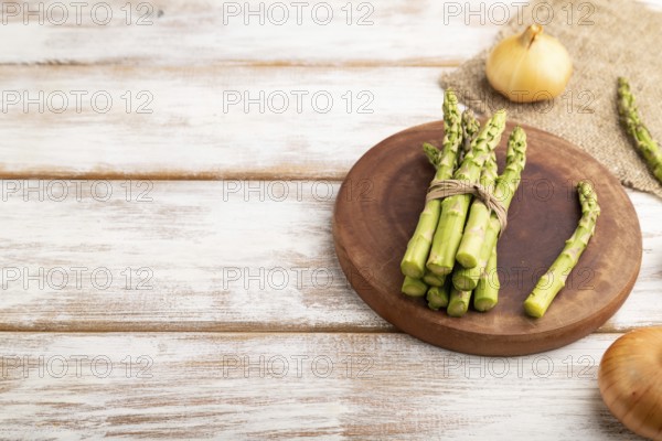 Bunch of fresh green asparagus, garlic, onion on white wooden background. Side view, copy space. harvest, healthy, vegan food, concept