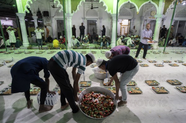 Volunteers distribute and arrange rows of 'iftar' meal for devotees to break their fast, during the holy month of Ramadan, at Burha Jame Masjid, on March 13, 2024 in Guwahati, Assam, India, Asia