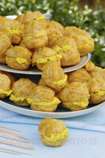 Swabian cuisine, mini cream puffs filled with goat's cream cheese, cream cheese éclairs, profiterole arranged on plate, shortbread, oven cakes, choux pastry, pastry, hearty, salty, choux pastry, baked, from the oven, vegetarian, bake, from the oven, typical Swabian reinterpreted, party pastry, finger food, appetisers for on the go, traditional cuisine reinterpreted, food photography, Germany, Europe