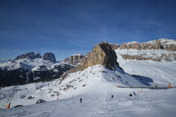 View of a ski resort piste with people skiing in Dolomites in Italy. Ski area Belvedere. Canazei, Italy, Europe