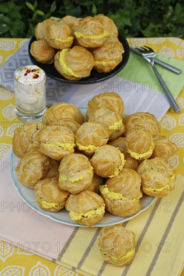 Swabian cuisine, mini cream puffs filled with goat's cream cheese, cream cheese éclairs, profiterole arranged on plate, shortbread, oven cakes, choux pastry, pastry, hearty, salty, choux pastry, baked, from the oven, vegetarian, bake, from the oven, typical Swabian reinterpreted, party pastry, finger food, appetisers for on the go, traditional cuisine reinterpreted, forks, food photography, Germany, Europe