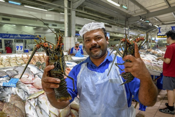 Seller on the fish market with two lobsters, Abu Dhabi City, Emirate of Abu Dhabi, United Arab Emirates, Asia