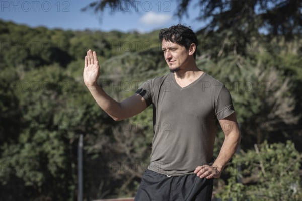 Portrait of a man practicing the third posture of the Bai Hu program, the static stance Santi Shi, focusing on pushing strength, outdoors