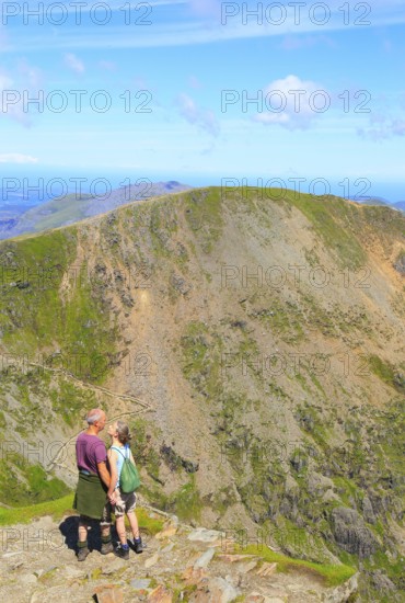 Man and woman enjoying view from summit of Mount Snowdon, Gwynedd, Snowdonia, north Wales, UK