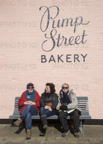 People sitting outside on sunny winter day Pump Street bakery, Orford, Suffolk, England, UK