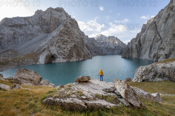 Tourist at the blue mountain lake between rocky steep mountain peaks, Kol Suu Lake, Sary Beles Mountains, Naryn Province, Kyrgyzstan, Asia