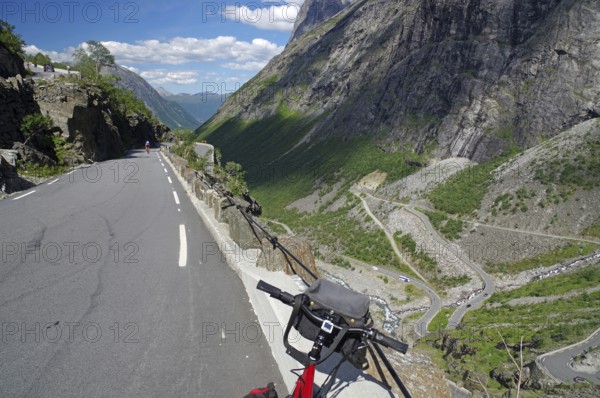 A mountain road winding through the landscape with a bicycle in the foreground, Trollstigen, Andalsnes, Norway, Europe