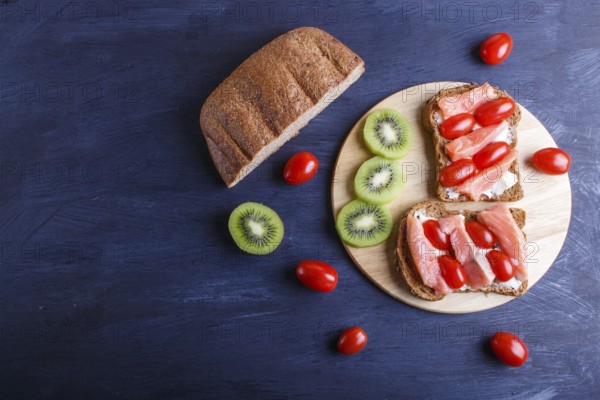 Smoked salmon sandwiches with butter on dark wooden background. cherry tomatoes. top view, copy space