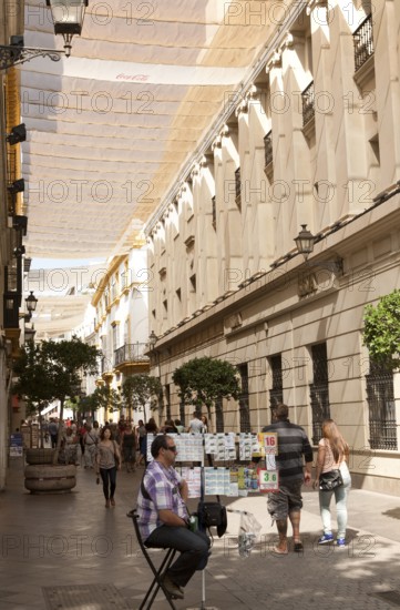 Fabric spread over buildings to provide shade in busy shopping street called Velazquez in central Seville, Spain, Europe